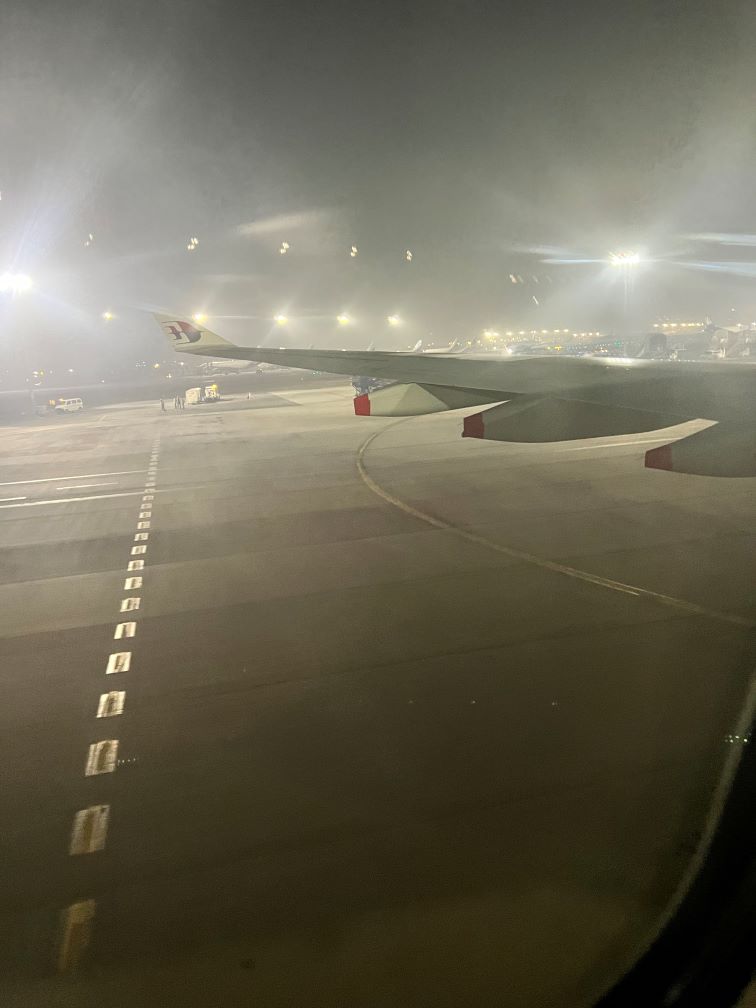 A very foggy airport runway with an aeroplane wing in the middle.